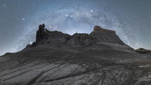 Unrecognizable person silhouette standing under the vast Milky Way in the Utah desert, highlighting