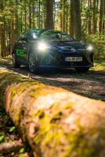 Black vehicle with headlights switched on on a forest path, Deer E- Carsharing, Calw, Black Forest,