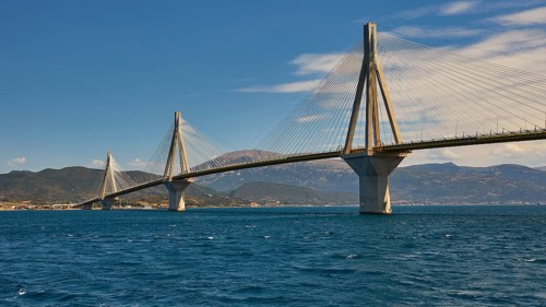 Cable bridge stretches across wide sea with slightly cloudy sky, Rio-Antirrio cable bridge, Patras,