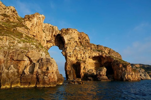 A majestic rock formation with an arch over the sea, morning light, Tsichli Babas islet, Navarino