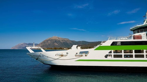 Large ferry with green accents, calm blue sea and mountain scenery in the background, Rio-Antirrio