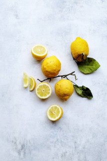 Top view of bright yellow lemons, some whole and some sliced, artistically arranged on a textured