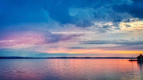 A calm lake at sunset with blue and pink colours in the sky, Übersee, Chiemsee