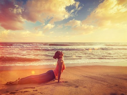 Vintage retro effect filtered hipster style image of Yoga outdoors on beach, woman practices