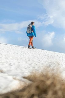 A lone trekker strides across a snowy landscape in the picturesque Pyrenees mountains, basking in
