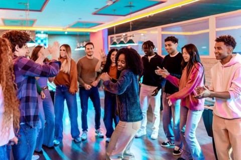 Multiethnic friends dancing and having fun together in a vibrant bowling alley, enjoying the music