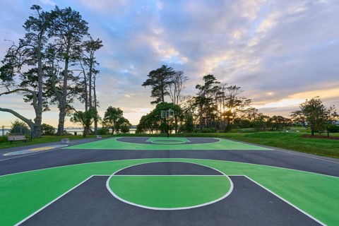 A green basketball court in a natural setting with trees and a dramatic sunrise sky, Coyle Park,