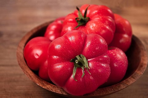 Pink tomatoes, in a rustic wooden bowl, close-up, no people
