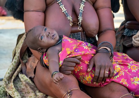 Baby in the arms of a Himba woman, traditional Himba village, Kaokoveld, Kunene, Namibia