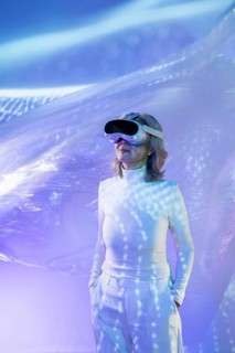 An elderly Asian woman experiencing the metaverse, wearing a VR headset in a dynamic, futuristic