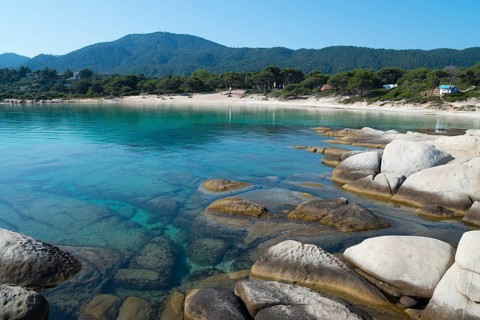 Crystal clear water and rocks in front of wooded mountains, Karidi beach, Karydi, Vourvourou,