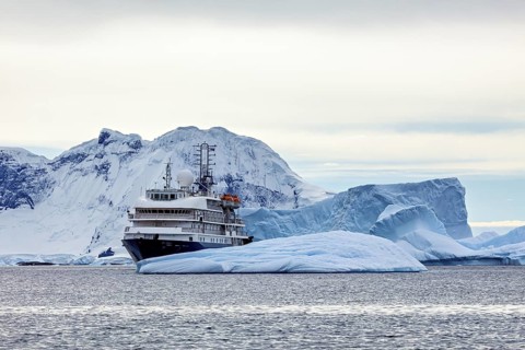 A large ship navigates through icy waters, surrounded by impressive glaciers, cruise ship underway