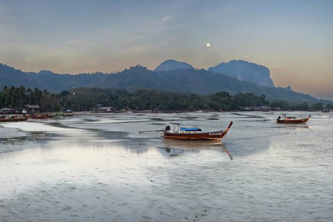 Before sunrise, longtail boats lie at low tide in the harbour at Sivalai Beach, Koh Mook Island,
