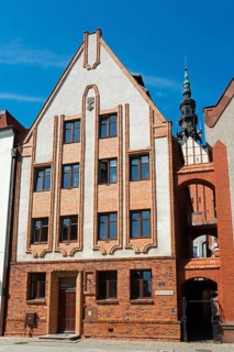 An imposing historic building with vertical structures, decorated with brick elements, against a