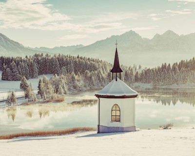 Chapel by the lake in the wintry snow-covered Allgäu near Halblech in front of an impressive