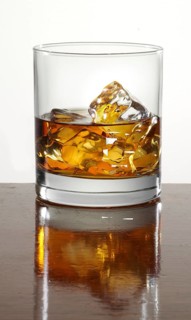 Whisky neat on ice cube cubes in a tumbler on a bar counter, studio shot