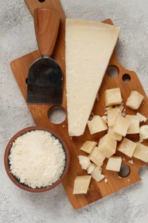 Freshly sliced and grated cheese, parmesan cheese, Gran gusto. Grana padano. on a wooden chopping