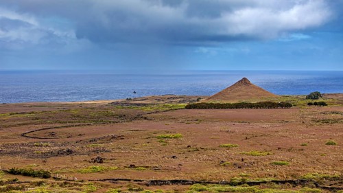 Lonely coastal landscape with a single hill under cloudy sky, The landscape of Easter Island in the