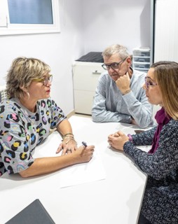 A woman and a couple with intellectual disabilities sit in an supervision meeting, engaged in