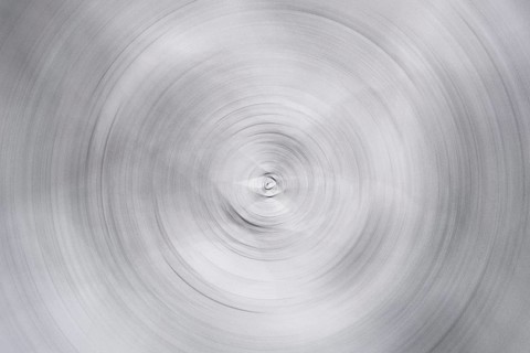 A distorted photograph showcasing an abstract spiral pattern in monochrome. The concentric circles