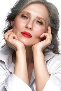 Portrait of a beautiful elderly woman in a white shirt with classic makeup and gray hair