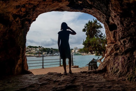 Tourist shielding her eyes from the sun while enjoying the view of the port of puerto cristo,