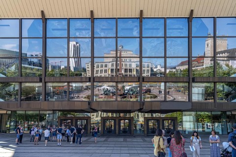 Mendebrunnen and Leipzig Opera are reflected in the façade of the Gewandhaus on Augustusplatz,