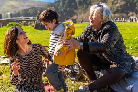 Mother, grandmother, and child enjoying a sunny day at the park, laughing and playing together in a