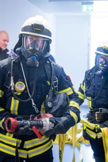 Two firefighters are preparing for a mission with hose and full equipment, fire brigade exercise on