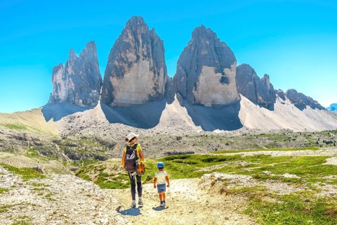 Tourists hiking on a trail with the tre cime di lavaredo in the background, dolomites, italy