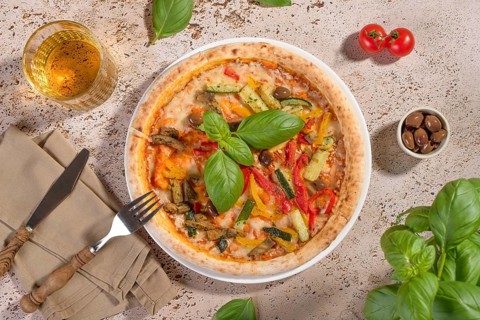Enjoy a delicious vegetarian pizza topped with fresh basil, zucchini, eggplant, and bell peppers.