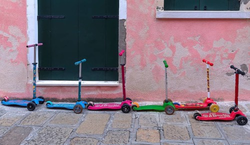 Colourful children's scooters in front of a kindergarten wall, Venice, Veneto, Italy