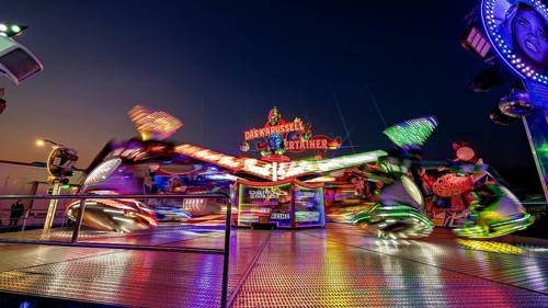 Blurred carousel in lively motion at a fair at night, carousel and hustle and bustle of summer