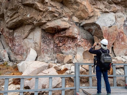 Tourist taking pictures, colored hands at the wall of the canyon, Cueva de las Manos, prehistoric