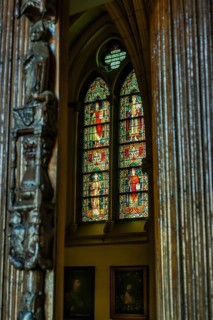A view through a carved wooden pillar onto a luminous stained glass window in a church