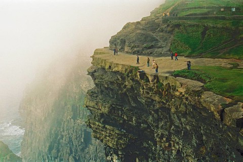 People on the edge of a cliff, there was no fence back then, Cliffs of Moher, County Clare,