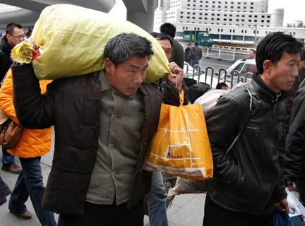 Beijing, CHN, 23.02.09 - A Chinese man carries his heavy luggage to the train station, CHINA