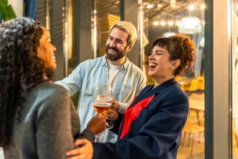 Multi-ethnic happy modern friends congratulating a woman during night party on bar terrace