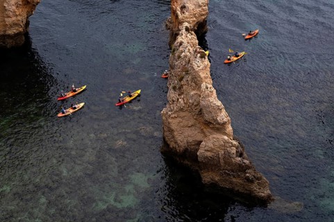 Kayaker, kayaks, kayaking, guided tour through grottos, rocks in the sea, Ponta da Piedade, Lagos,