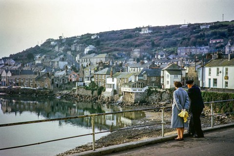 Man and woman looking across the harbour, Mousehole, Cornwall, England, UK November 1961
