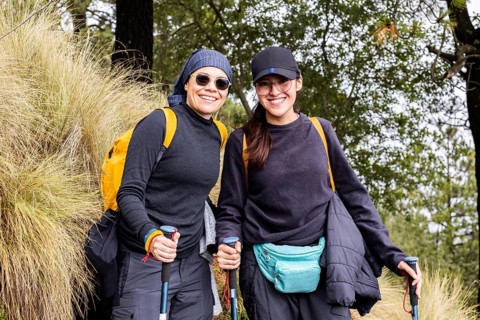 A cheerful pair of hikers take a break on a scenic forest trail. Dressed in outdoor gear and