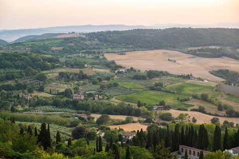 View from Montepulciano into a typical Tuscan landscape in Val d'Orcia with hills, trees, fields,