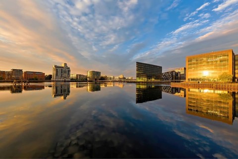 Breite Wasserfläche spiegelt moderne Architektur und Himmel am frühen Morgen, Kopenhagen, Dänemark