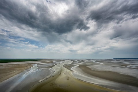 View from the rocky island, monastery island of Le Mont Saint Michel onto a wide mudflat landscape