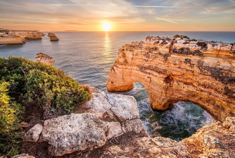 Sunrise view of Praia da Marinha beach in Algarve, Portugal, with a limestone sea arch, Atlantic
