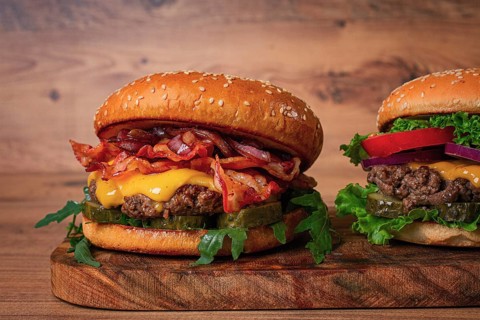 Two burgers with beef patty, fried bacon, cheddar cheese, tomatoes, homemade, no people