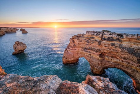 Sunrise at Praia da Marinha beach in Algarve, Portugal, with ocean cliffs, sea stacks and quiet