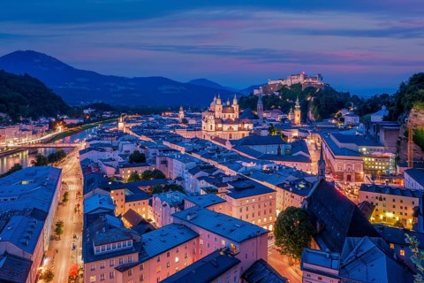 A wide aerial perspective of Salzburg, Austria, featuring the Salzach river flowing past the