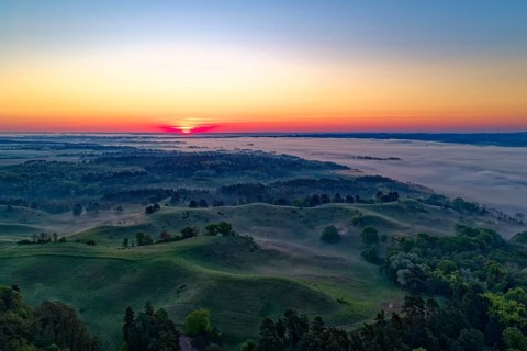 Sunrise over the hilly landscape of the Uckermark on the edge of the Oder Valley and morning fog