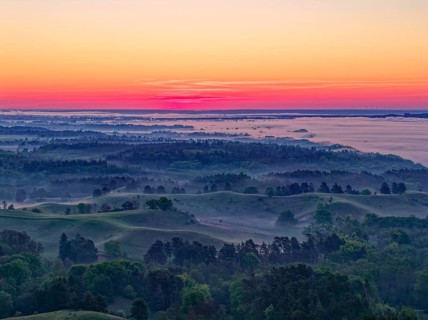 The hilly landscape of the Uckermark on the edge of the Oder Valley in morning light and fog above